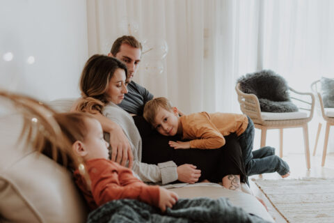 Femme enceint avec son mari et enfants sur un canapé.