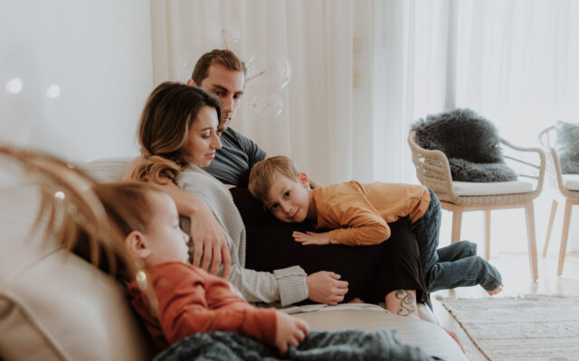 Femme enceint avec son mari et enfants sur un canapé.
