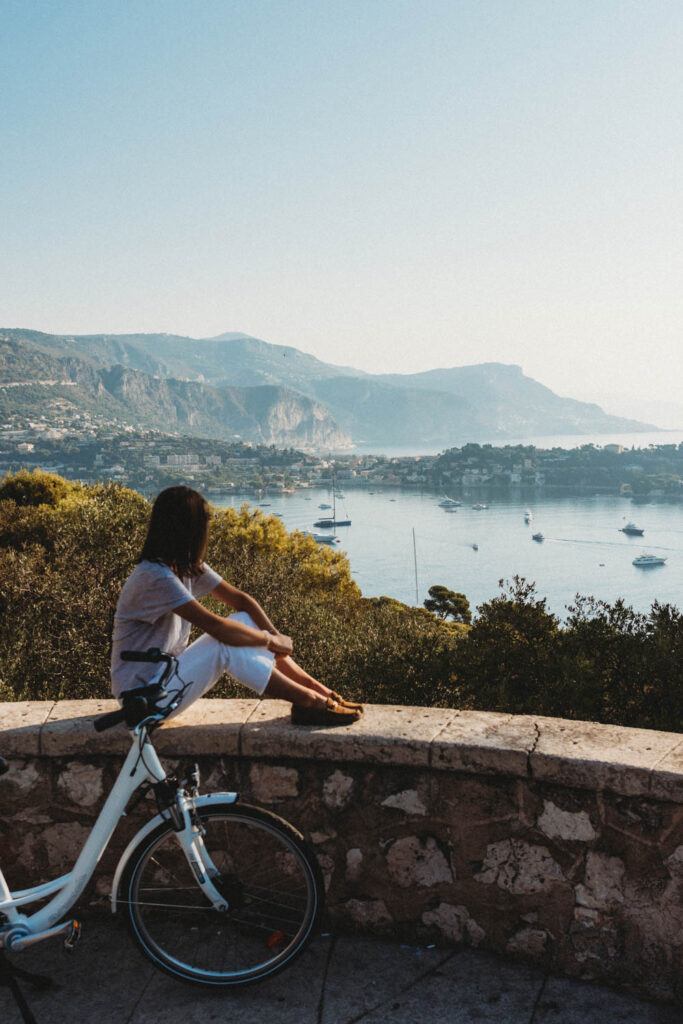 Girl sitting on stone wall looking at Villefranche sur mer.