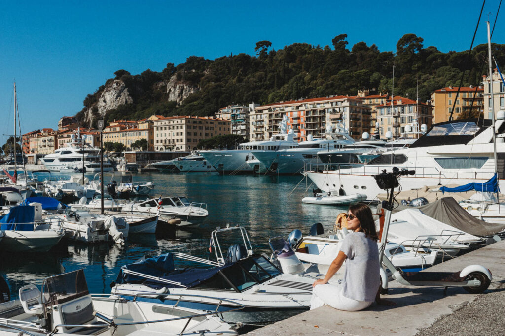 Girl sitting in Port of Nice with the view of Castle Hill