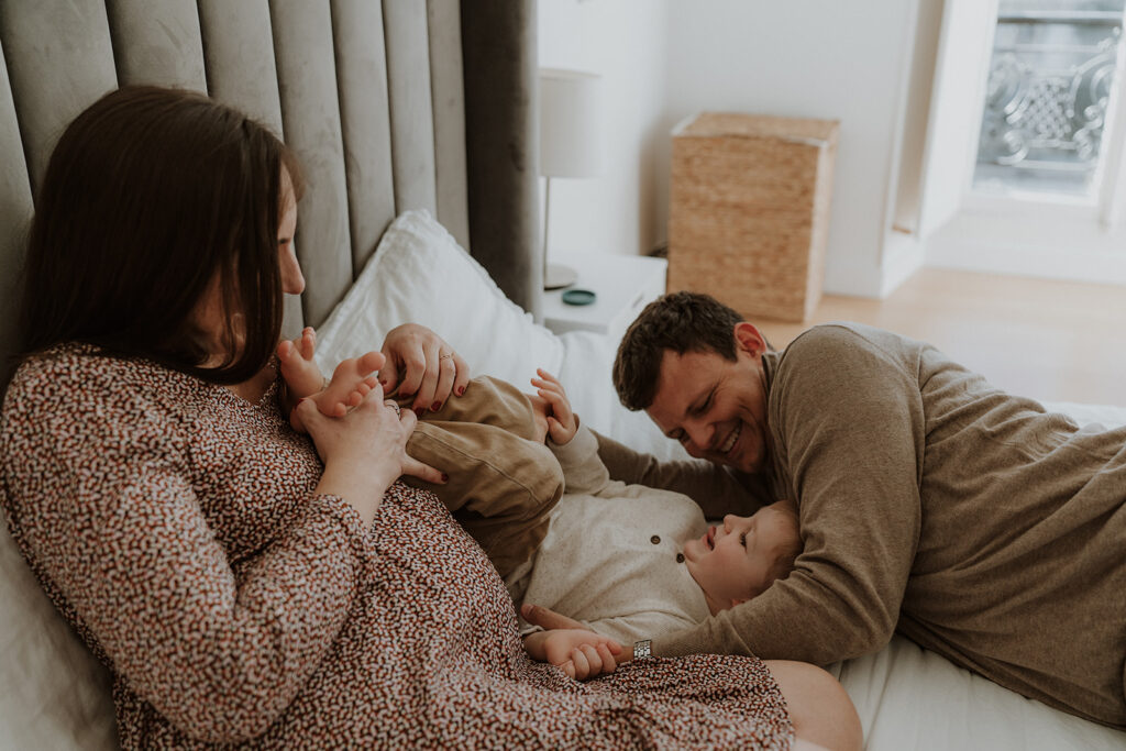 Une femme enceint avec son mari et enfant sur le lit. Photographe grossesse Anna Leak