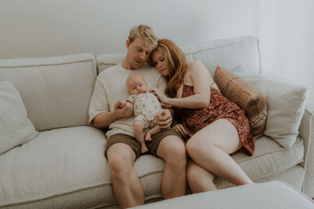 Maman et papa avec son nouveau-né sur canapé à la maison
